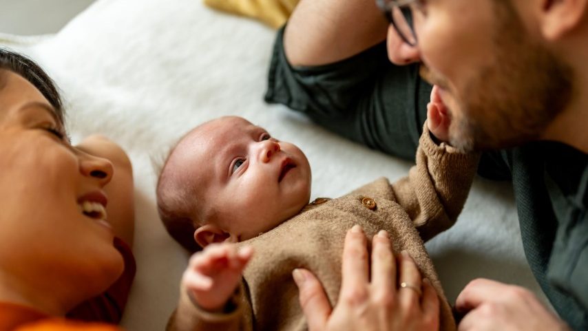Casal deitado com um bebê pequeno (Foto: Getty Images)