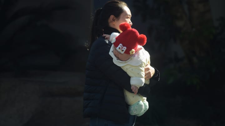 Um pai caminha pela rua segurando uma criança em Hangzhou, China, em 17 de janeiro de 2025. (Foto: Costfoto | Nurphoto | Getty Images)