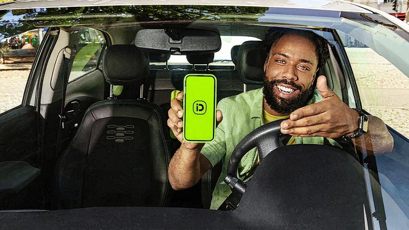 Homem em terno fala ao microfone durante apresentação em um palco com gráfico ao fundo (Foto: Reprodução)