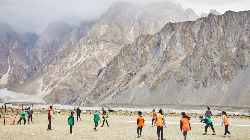 Jogadoras da Passu Youth Football Academy treinam em seu campo de futebol, situado no povoado de Passu e rodeado pelos Passu Cones, montanhas com picos de 6.100 metros de altura. (Foto: Anna Huix)