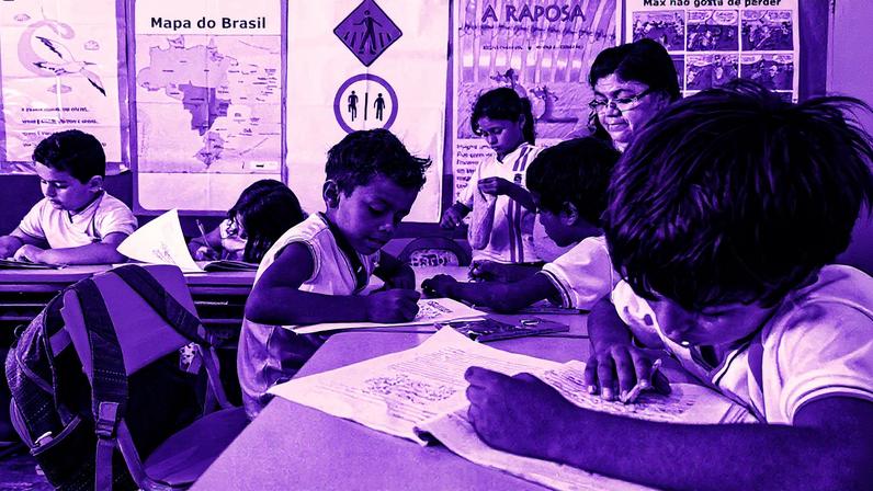 Sala de aula de escola municipal com alunos sentados em carteiras e um professor na frente (Foto: Reprodução)