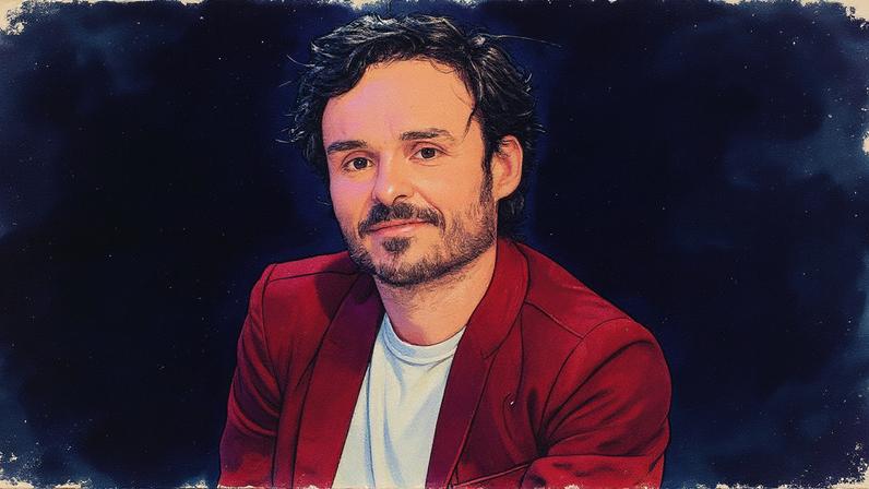 Homem em pé em um ambiente interno, vestido com camisa e gravata, olhando para a câmera (Foto: Reprodução)