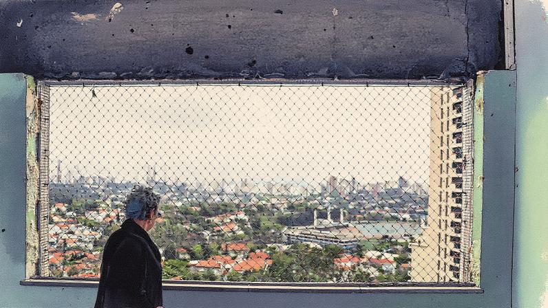 Rosa Maria Vieira ao lado de uma janela quebrada de seu quarto, com vidraças de um prédio danificadas após vendaval em São Paulo (Foto: Reprodução)