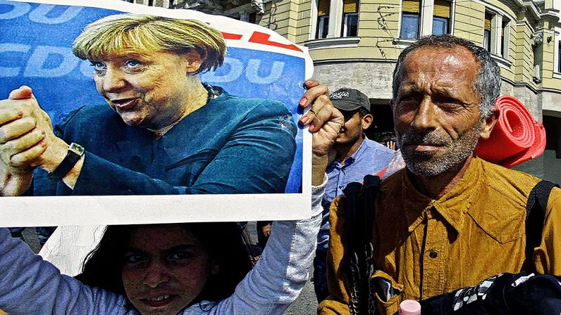 Menina imigrante segura cartaz com o rosto da então primeira-ministra da Alemanha, Angela Merkel, em Budapeste (Foto: Reprodução)