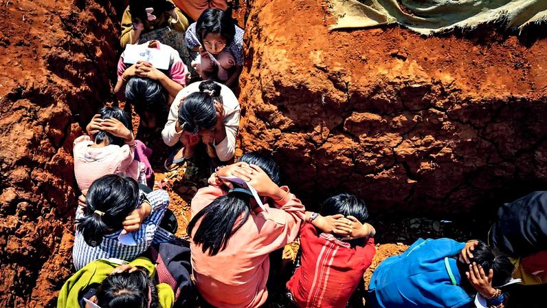 Grupo de crianças se abriga em trincheiras escavadas ao lado da escola durante um simulacro (Foto: Reprodução)