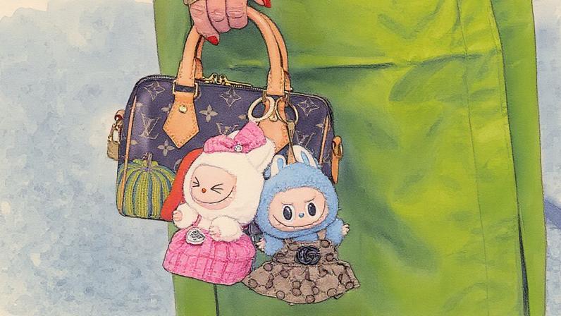 Bolsa mini top-handle da Louis Vuitton em lona revestida marrom com alças de couro vachetta em tom claro e motivo de abóbora amarelo e laranja, acompanhada de dois charms de pelúcia Labubu, durante a Copenhagen Fashion Week em 07 de agosto de 2025 (Foto: Reprodução)