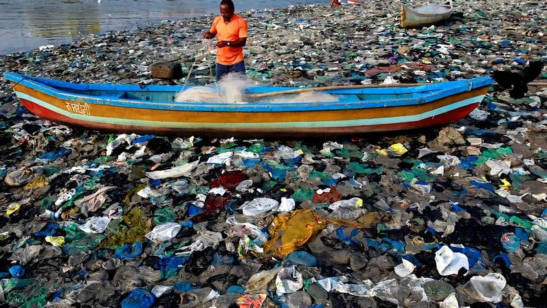 Pescador prepara sua rede nas margens do Mar Arábico, cercado por sacos de plástico, em Mumbai (Foto: Reprodução)