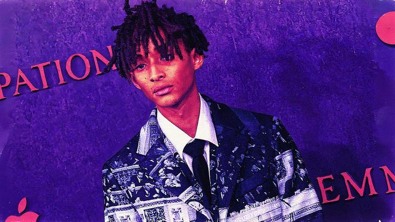 Jaden Smith em evento, usando uma jaqueta e calça pretas, com cabelo preso em um coque (Foto: Reprodução)