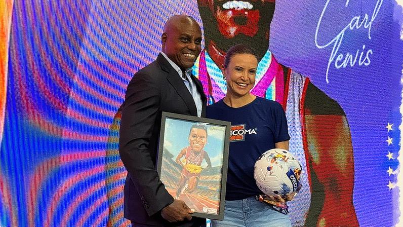 Carl Lewis e Maurren Maggi posaram no palco para celebrar o encontro na COB Expo 2025. (Foto: Vinícius Harfush/Lance!)