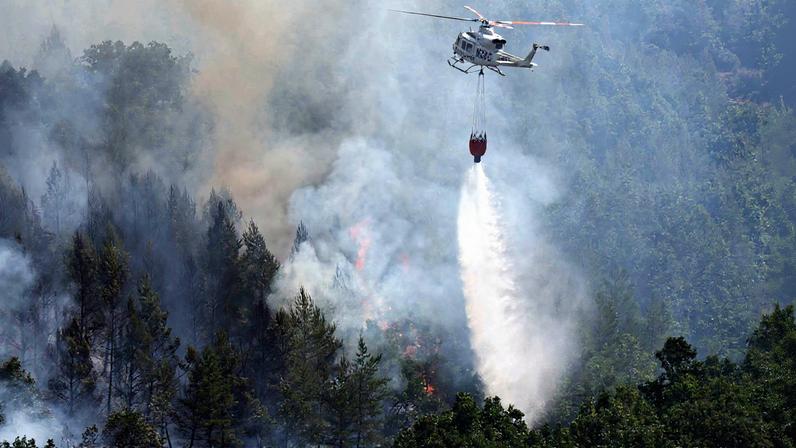 Helicóptero dos bombeiros lança água sobre incêndio em Garano, no noroeste da Espanha (Foto: Reprodução)