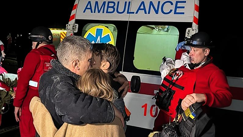 A father hugs his children after their mother was killed during a Russia drone strike in Kharkiv amid Russia's attacks on Ukraine.