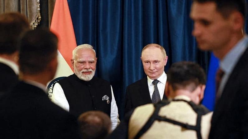 Modi and Putin stand side-by-side, looking ahead, with a crowd in front of them.